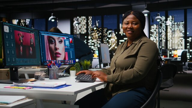 Organized creative workspace for black graphic designer photographer, featuring dual monitors setup with digital editing tools. Photo editor software and AI chatbot for content creation. Camera A.