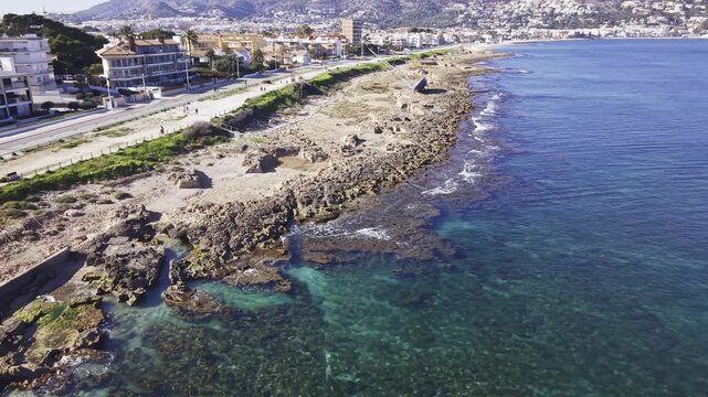 Aerial view of rocky coast and capsized sailboat stranded on rocky Mediterranean coastline