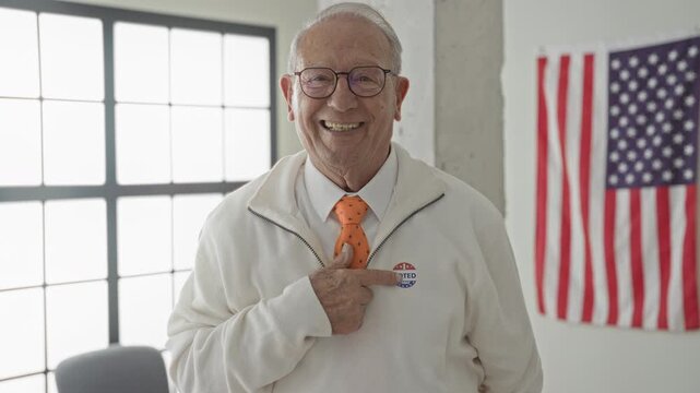 Man points finger to voted sticker on sweater inside civic building with american flag visible; civic duty pride.