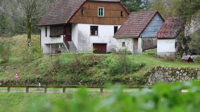rain falling in on small house along the road with plants moving in the foreground soca valley julian alps slovenia europe european iconic historic home trees mountains