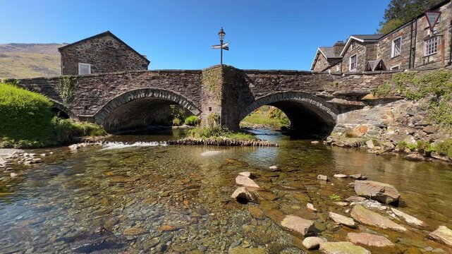 Historic stone arch bridge over the River Glaslyn in Beddgelert village, Snowdonia, Wales, UK