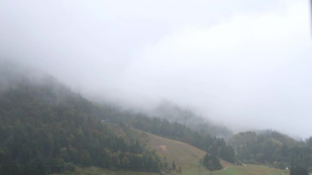 rain falling in the julian alps mountains in tarvisio, italy on the border with slovenia church rooftops trees hills mist weather raining storm alpine travel destination