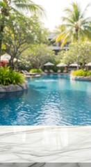 Fototapeta premium Empty Marble Table Overlooking Blurred Tropical Resort Swimming Pool