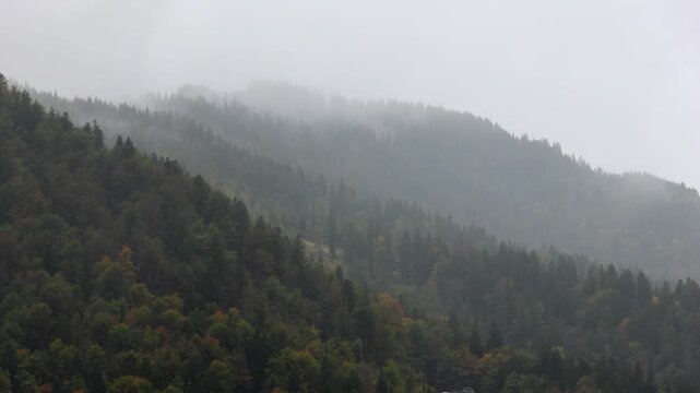 rain falling in the julian alps mountains in tarvisio, italy on the border with slovenia church rooftops trees hills mist weather raining storm alpine travel destination