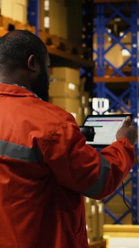 Vertical Video African american personnel scanning barcodes and shipment tags on tablet, checking AWB labels placed on cardboard boxes before delivery and transportation. Fulfillment center operations