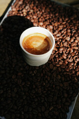 Naklejka premium Gourmet Coffee Presentation White Cup of Espresso on Bed of Roasted Beans
