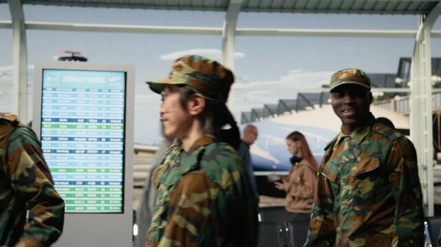 Walking, international travel and multiethnic military squad talking in airport. Discussing, homecoming and diverse army soldiers waiting in departure terminal lounge for plane, camera A