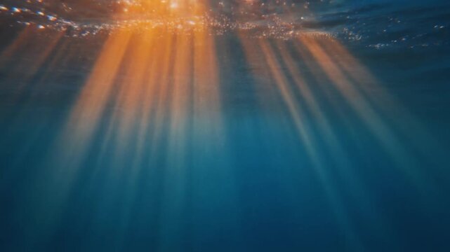 Golden sunset light rays shining underwater in deep blue ocean