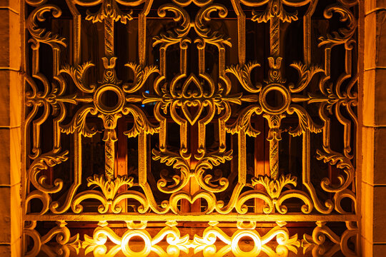 Ornate ironwork gate illuminated by warm light in evening ambiance
