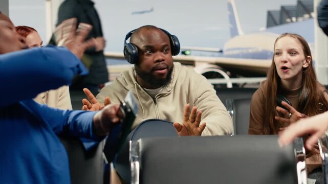 Multiethnic group of friends in airport chatting, waiting for departure gate to open. Travel buddies having fun in air transportation transit hub, preparing for international flight, camera A
