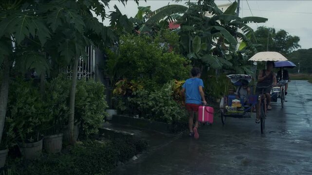 Asian transgender woman with luggage getting on a tricycle taxi on a rainy day in the countryside