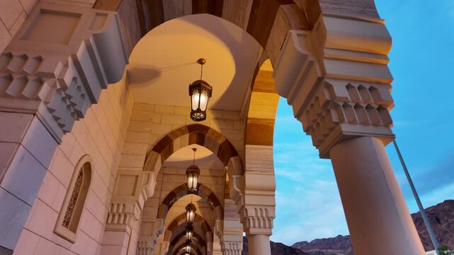 Under the arcades of Sayed Al-Shuhada Mosque, ablution fountains line the portico beneath, highlighting traditional Islamic architecture and intricate patterns in the holy city of Medina, Saudi Arabia