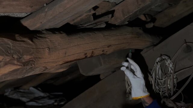 Pest control worker injecting insecticide into wooden beams