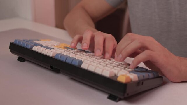 Typing in warm ambient light. Steady rhythm while coding with colorful keycaps at night. Closeup of hands working on keyboard under soft lighting with bokeh background