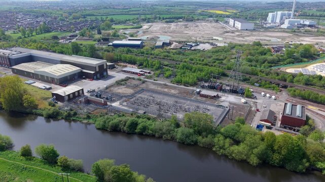 Aerial view of National Grid Ferrybridge A Substation with industrial buildings and power infrastructure near the river in Knottingley, England, United Kingdom.