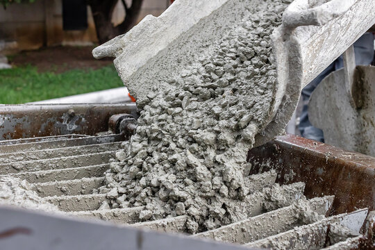 Wet concrete mixture with gravel unloading into pumping hopper, close up industrial construction process, cement transfer and building materials detail