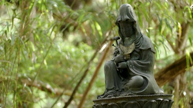 Stone Jizo Bosatsu Statue Wearing Red Bib in a Japanese Temple Garden