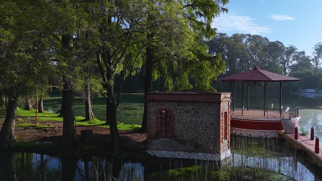 Chautla, Puebla: A vibrant red and white circular gazebo or kiosk built over a lake with green aquatic plants.
Lakeside viewpoint at the historic former Chautla Hacienda.