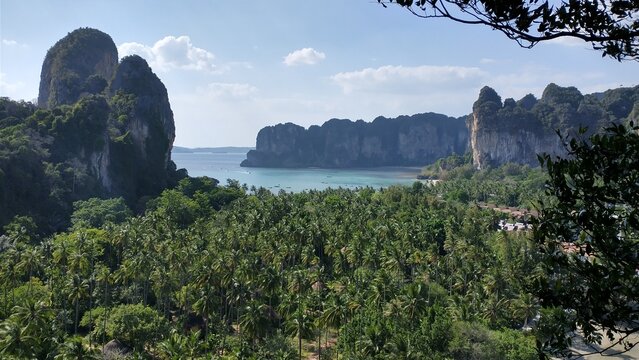 High-angle panoramic view of Railay Beach West in Krabi, Thailand. Tropical coastline with turquoise Andaman Sea, white sand, and lush limestone cliffs.