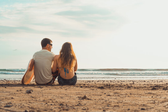 Surfer couple sharing quiet moment on beach