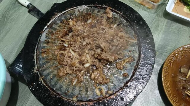 Sizzling Beef Slices and Onions Cooking on Round Griddle