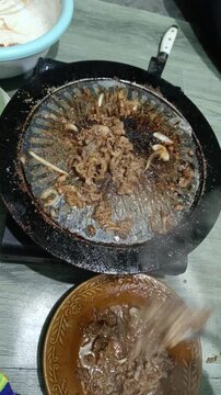 Cooking Sliced Beef and Onions on a Griddle with Chopsticks