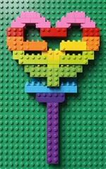 Naklejka premium Rainbow LEGO heart on green baseplate colorful and playful.