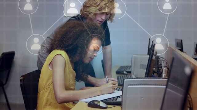 Learner writing at PC while mentor pointing and typing, causing network overlay growth for training