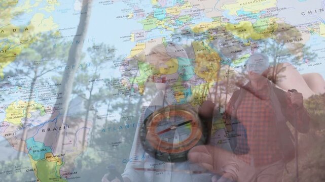 Male hiker bringing compass forward and checking heading, world map overlay guiding navigation