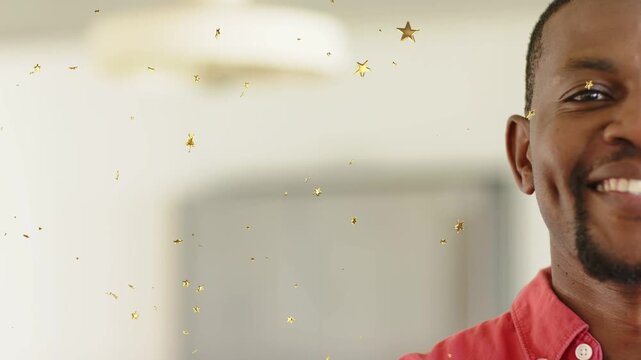 Gold star confetti drifting across camera revealing man smiling in red shirt for marketing