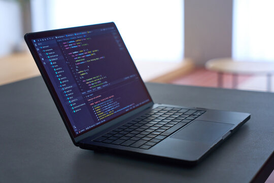 Programming code displayed on laptop screen on dark desk