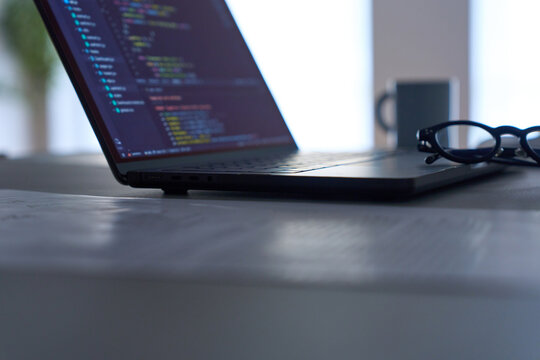 Programming code displayed on laptop screen on dark desk