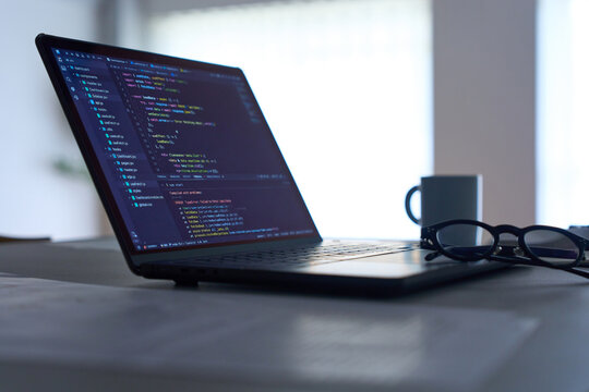 Programming code displayed on laptop screen on dark desk