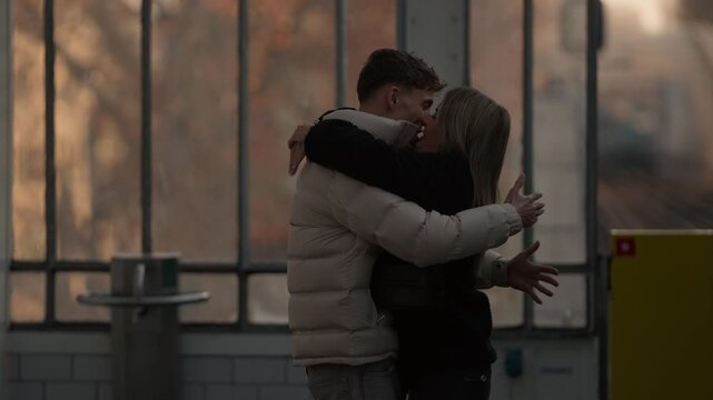 A young couple meets at a train platform in Paris France The man greets the woman as she arrives by train Handheld shot with a warm color grade.