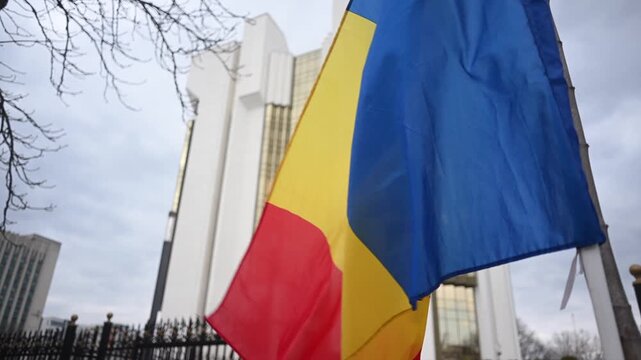 Moldovan flag waving dynamically in front of national government building footage.