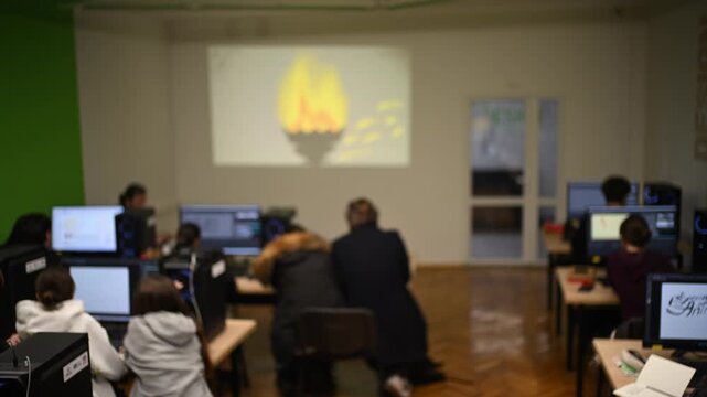 Students gathered in computer lab, focusing on projector screen showing animation.