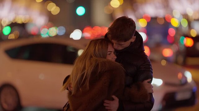 A young couple embraces in Paris at night with bokeh lights creating a romantic atmosphere The man and woman are standing on a street with blurred background enjoying a moment of affection in the city