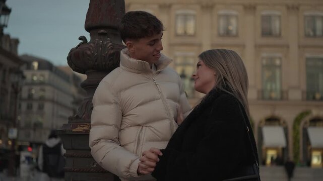 A young couple embraces in Paris France holding hands near a streetlight at dusk The Parisian architecture provides a romantic backdrop The clip captures a moment of love and affection in the heart of