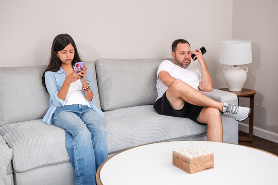 Family Members Using Smartphones While Sitting Together On Couch