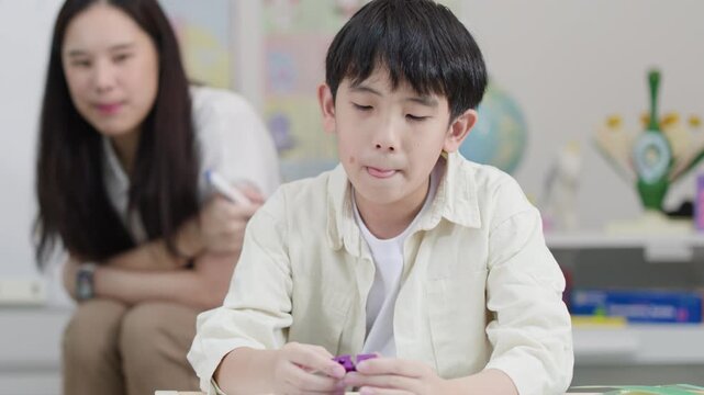 Young Asian Boy Playing with Plastic Blocks in a Classroom Setting