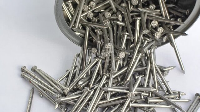 Close-up of many nails on a white surface, representing construction and manual labor concepts. White surface covered with detailed nails, representing an intriguing blend of order and chaos.