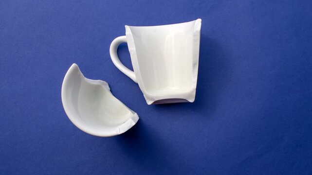 Detail of a broken white porcelain cup, symbolizing the poetry found in imperfection. Close-up of a broken white porcelain cup, expressing beauty in fragility on a light surface.