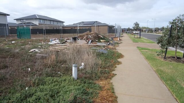 A pile of construction debris and rubbish illegally dumped on a vacant lot surrounded by new houses in Tarneit, Melbourne Australia. Messy, neglected land within growing suburban fringes.