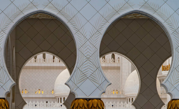 View of ornate white marble arches with gold palm leaf capitals and intricate floral patterns in Abu Dhabi, Abu Dhabi, United Arab Emirates.