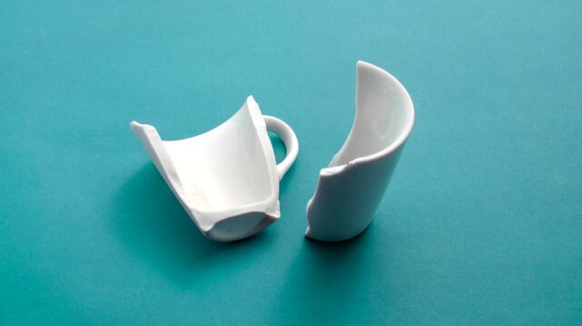 Detail of a broken white porcelain cup, symbolizing the poetry found in imperfection. Close-up of a broken white porcelain cup, expressing beauty in fragility on a light surface.