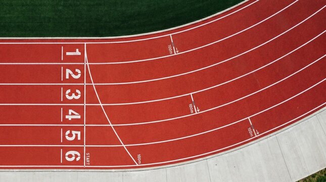 Top view of red running track with numbered lanes from one to six.