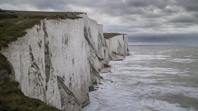 Dramatic White Chalk Cliffs Along the Coast with Lighthouse under Stormy Sky