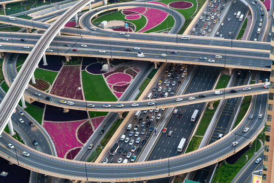 View of a complex multi-level highway interchange with heavy traffic, metro tracks, and decorative landscaped gardens Dubai, Dubai, United Arab Emirates.