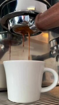 Low Angle Shot of Black Coffee Pouring From Coffee Machine Into White Cup