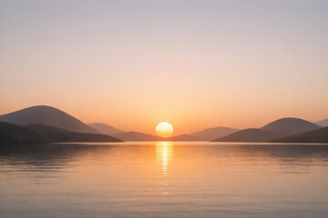 Naklejka premium Warm sunset over calm lake water with silhouetted mountain ranges and soft golden light reflecting on the surface at dusk